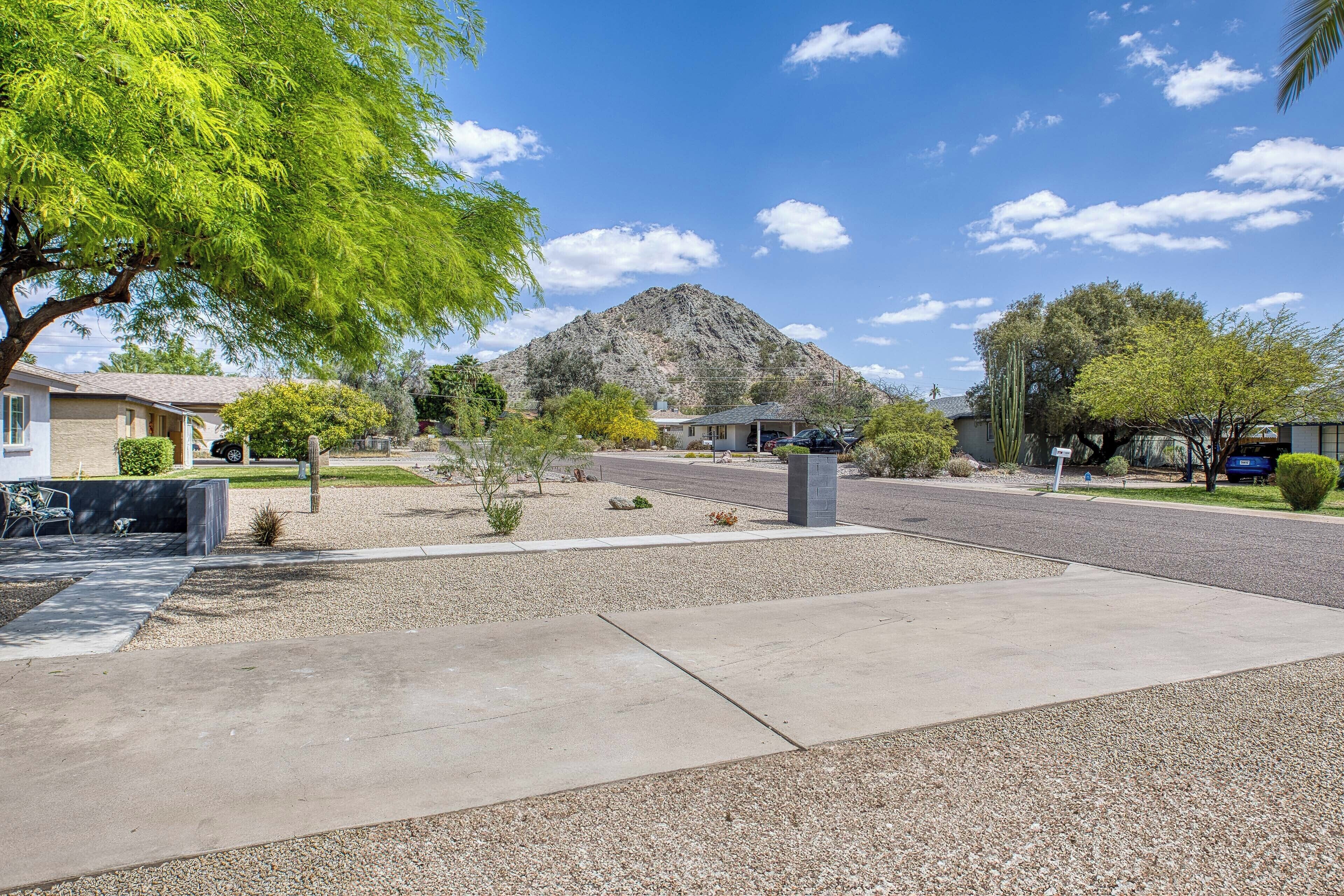 A residential street with houses, a mountain in the background, and a clear sky.