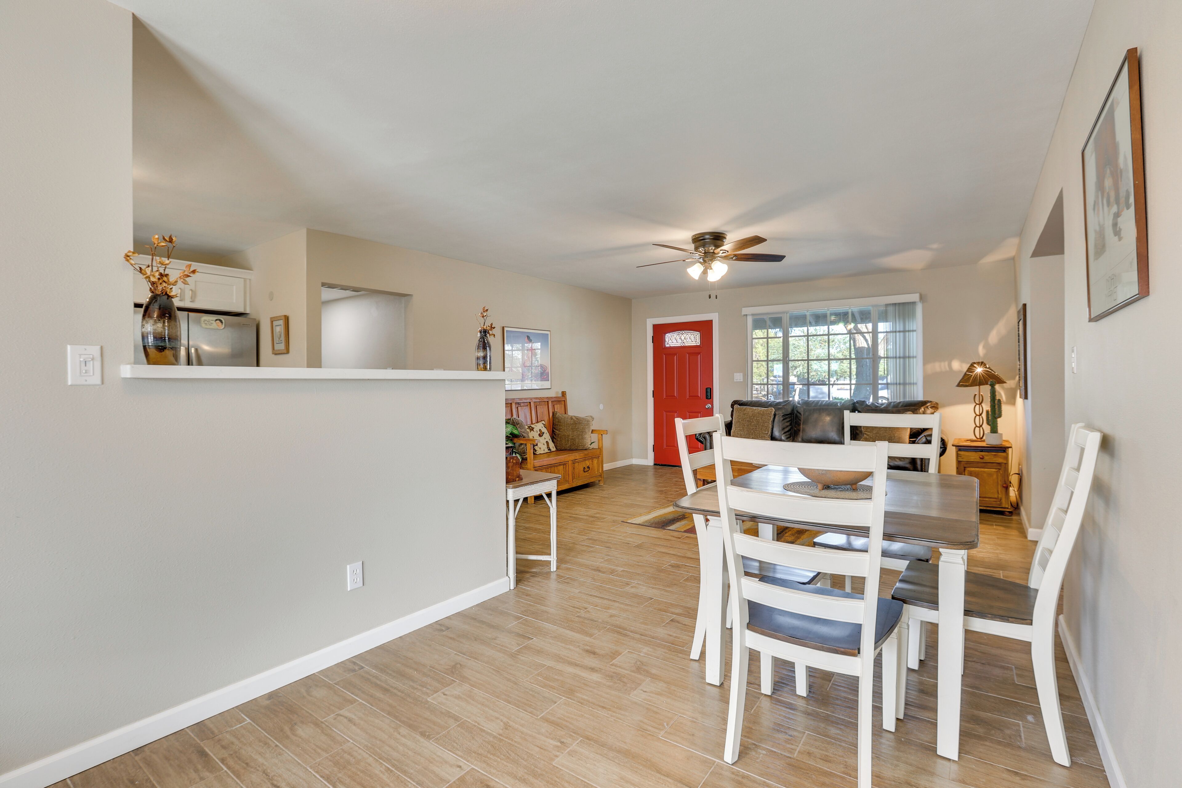 A spacious kitchen with a dining area, a ceiling fan, and a red door.
