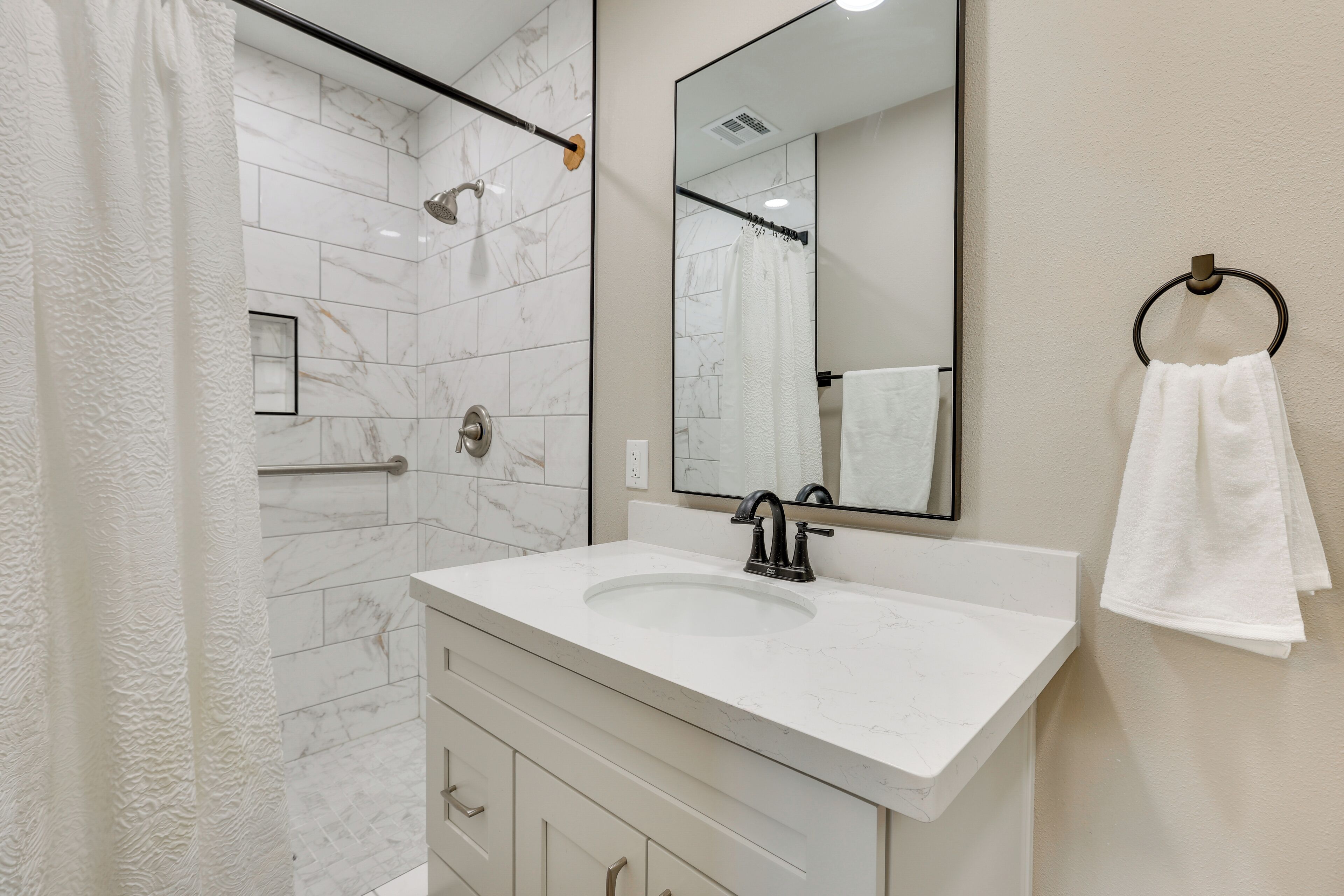 Une salle de bain moderne avec un lavabo en marbre blanc, un grand miroir et un porte-serviettes.