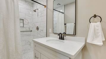 Une salle de bain moderne avec un lavabo en marbre blanc, un grand miroir et un porte-serviettes.