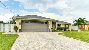 A single-story house with a garage, a paved driveway, and a well-maintained lawn.