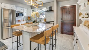 A modern kitchen with a central island, stainless steel appliances, and a wooden door. - Walk to Scottsdale Stadium: Remodeled Home! (Scottsdale)
