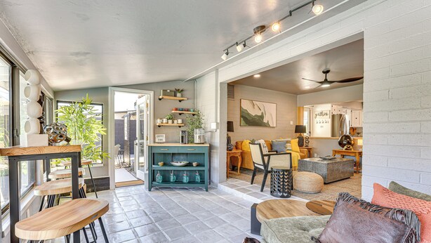 A spacious living area with a sofa, a coffee table, and a dining table with chairs. There is a kitchen area with a refrigerator and a dining table. - Walk to Scottsdale Stadium: Remodeled Home! (Scottsdale)