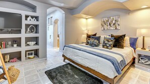 A bedroom with a large bed, built-in shelving, and a view of the hallway. - Walk to Scottsdale Stadium: Remodeled Home! (Scottsdale)