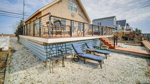 A two-story wooden house with a balcony, outdoor seating, and a staircase leading to the upper floor. - 2 Mi to Stone Harbor Beach: Lovely Bayfront Home (Cape May Court House)