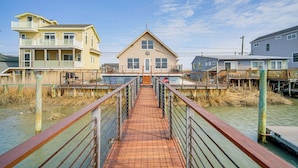 A wooden boardwalk leading to a two-story house with a balcony, surrounded by water and vegetation. - 2 Mi to Stone Harbor Beach: Lovely Bayfront Home (Cape May Court House)