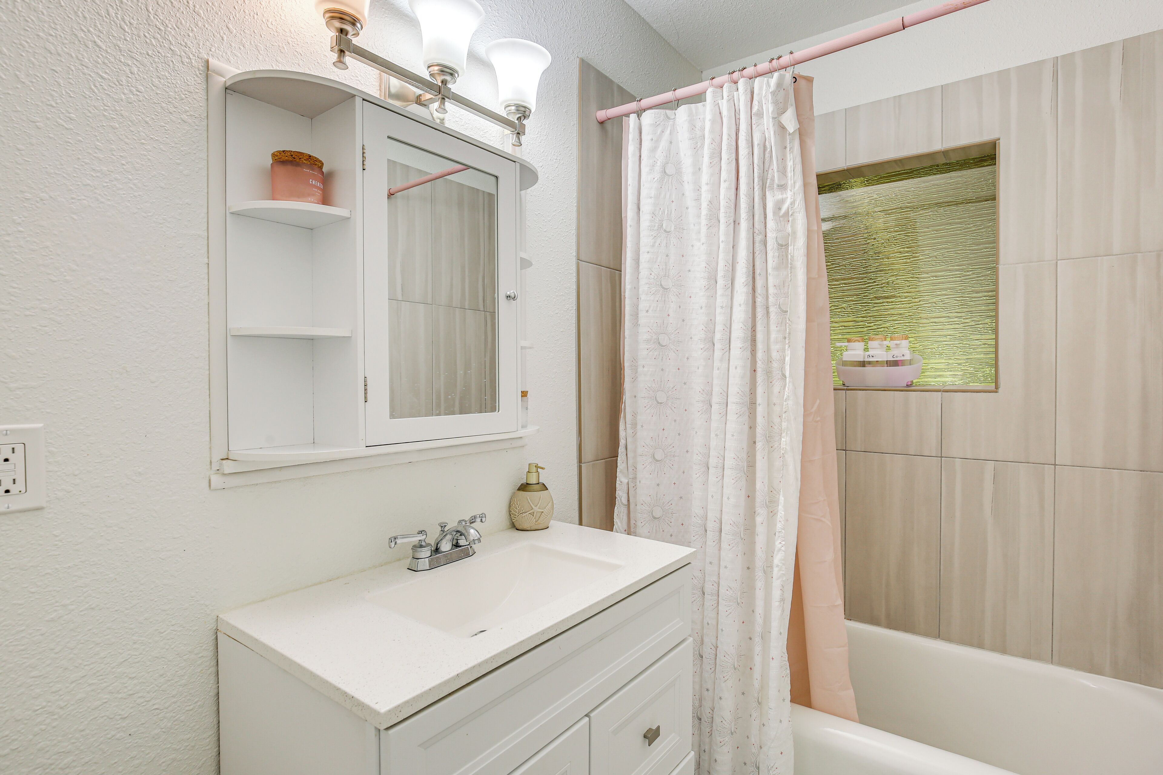 A bathroom with a white vanity, a mirror, a sink, and a shower curtain.