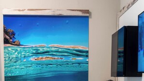 A hotel room with a large mural of a clear blue sea and coral reef, a bed with teal bedding, and a small desk with a kettle and books. - HOTEL ACQUAMARINA (Portoferraio)