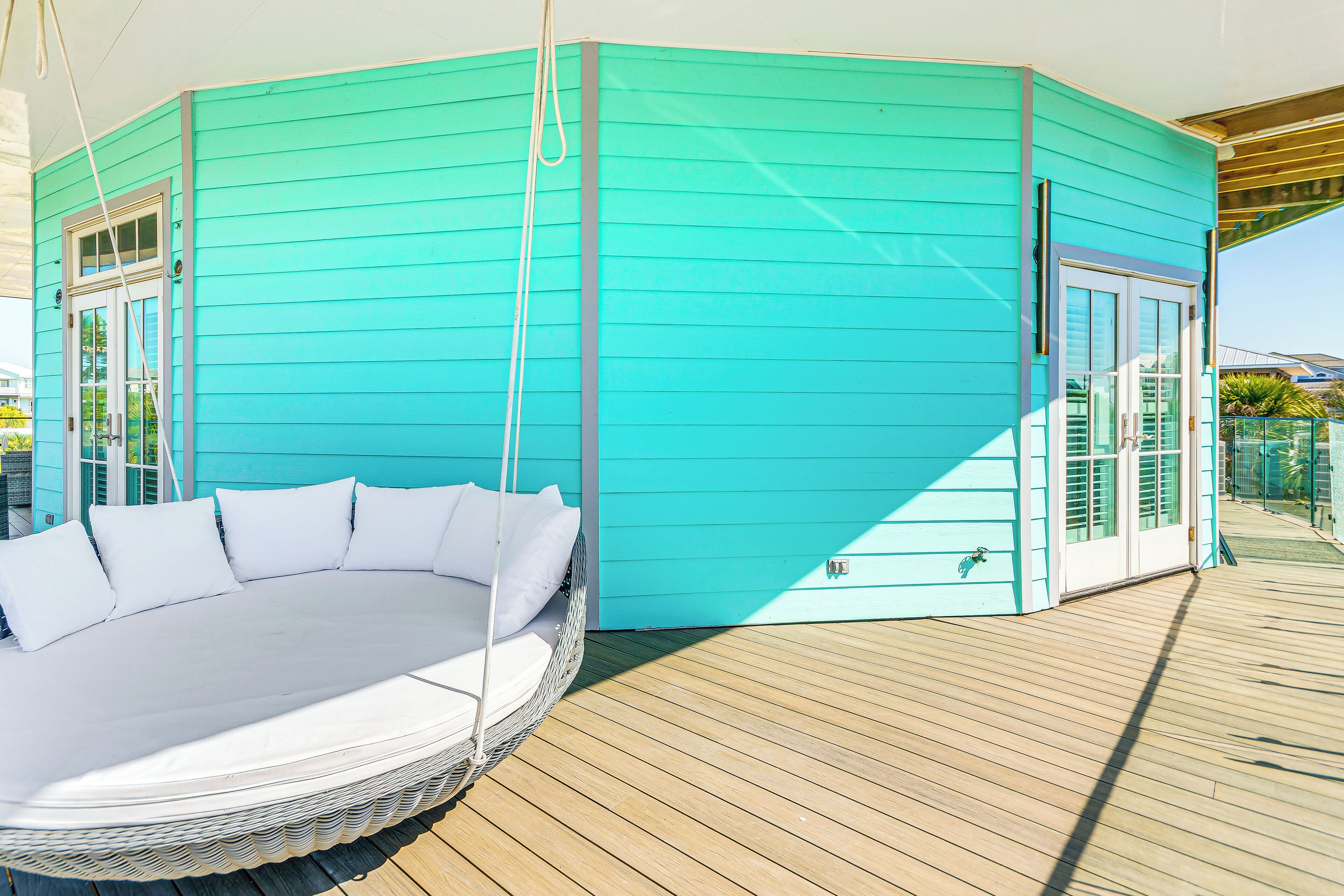 A turquoise building with a round outdoor seating area and a wooden deck.