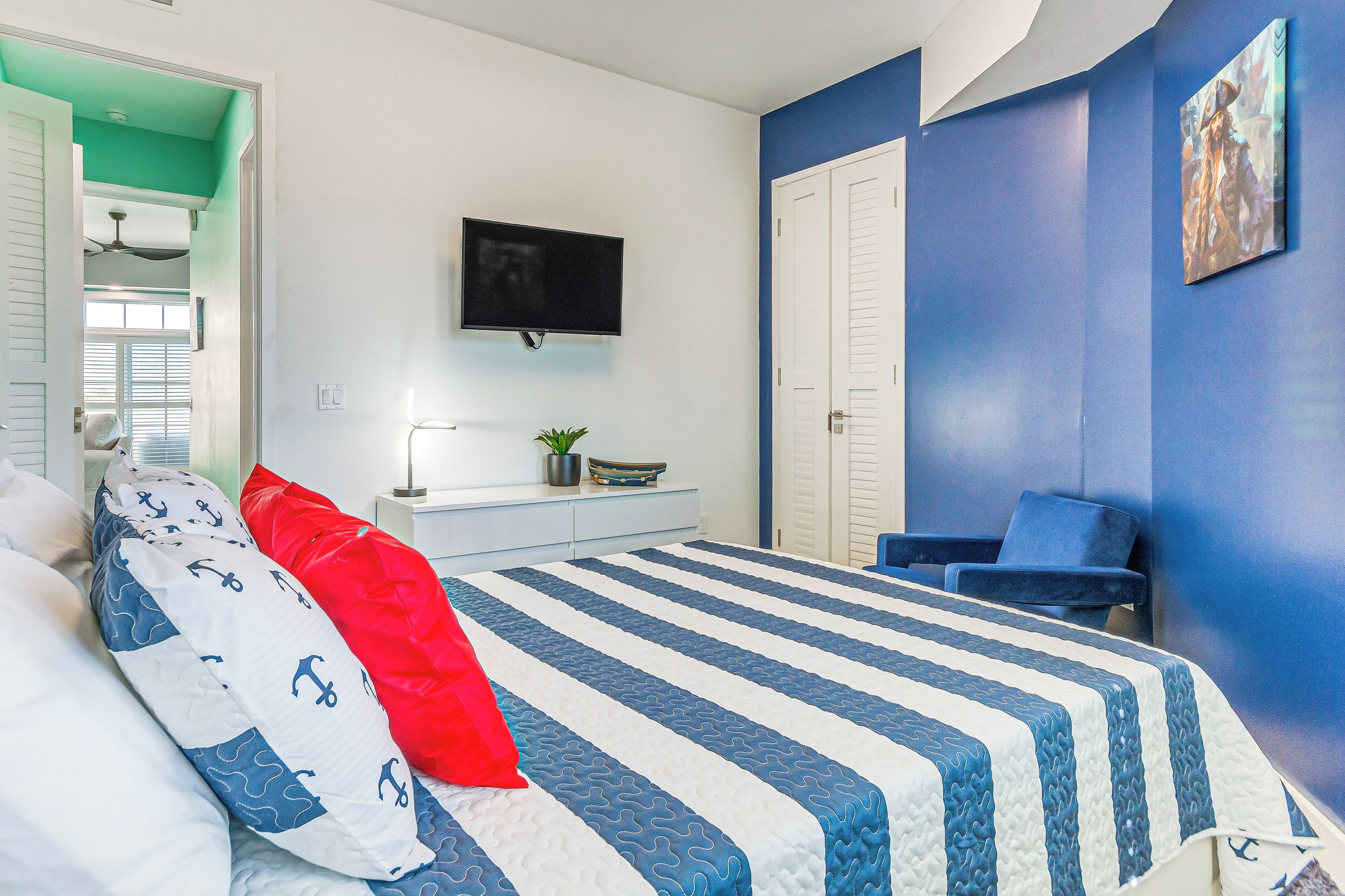 Ein Schlafzimmer mit einem Bett, einem Fernseher, einem Schreibtisch und einem Sessel.