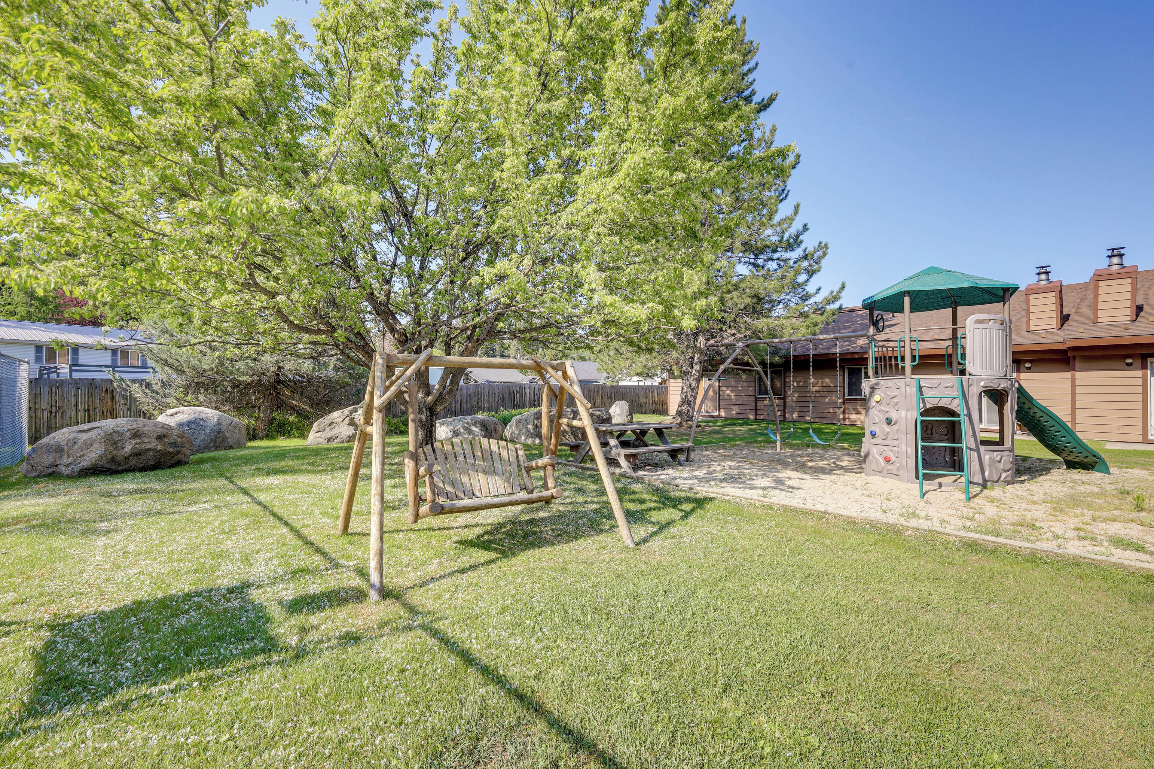 Un jardin avec une balançoire, une cabane et un toboggan.