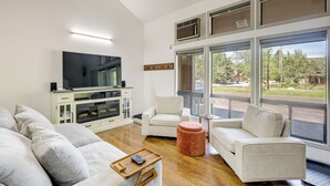 Een moderne woonkamer met een grote flatscreen televisie, een bank, twee fauteuils en een salontafel.