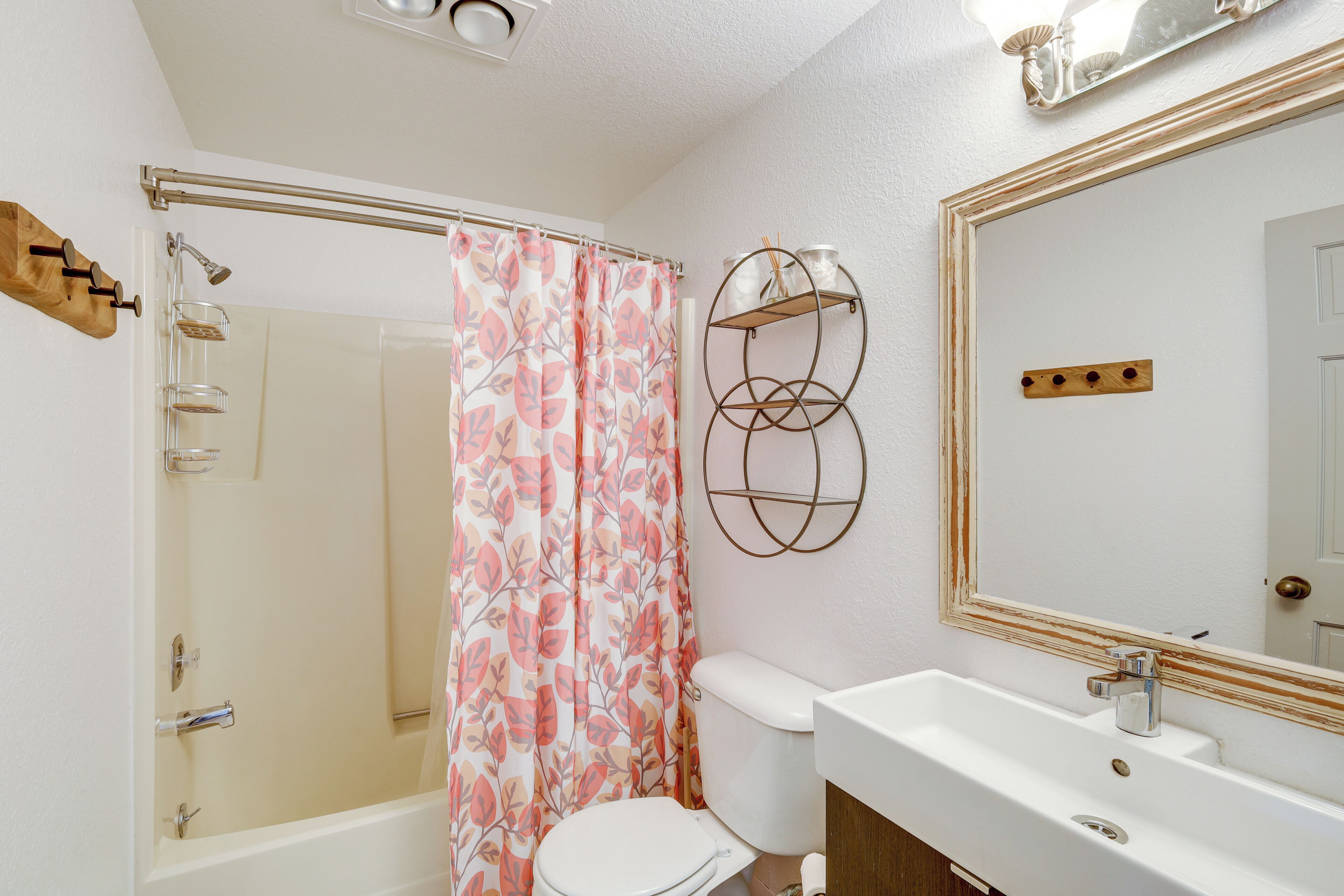 A bathroom with a shower, toilet, sink, and a mirror.