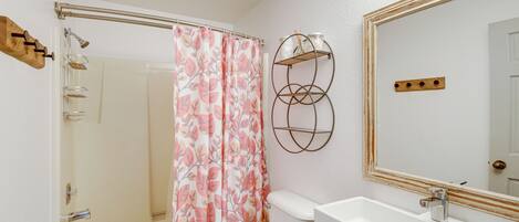 A bathroom with a shower, toilet, sink, and a mirror.