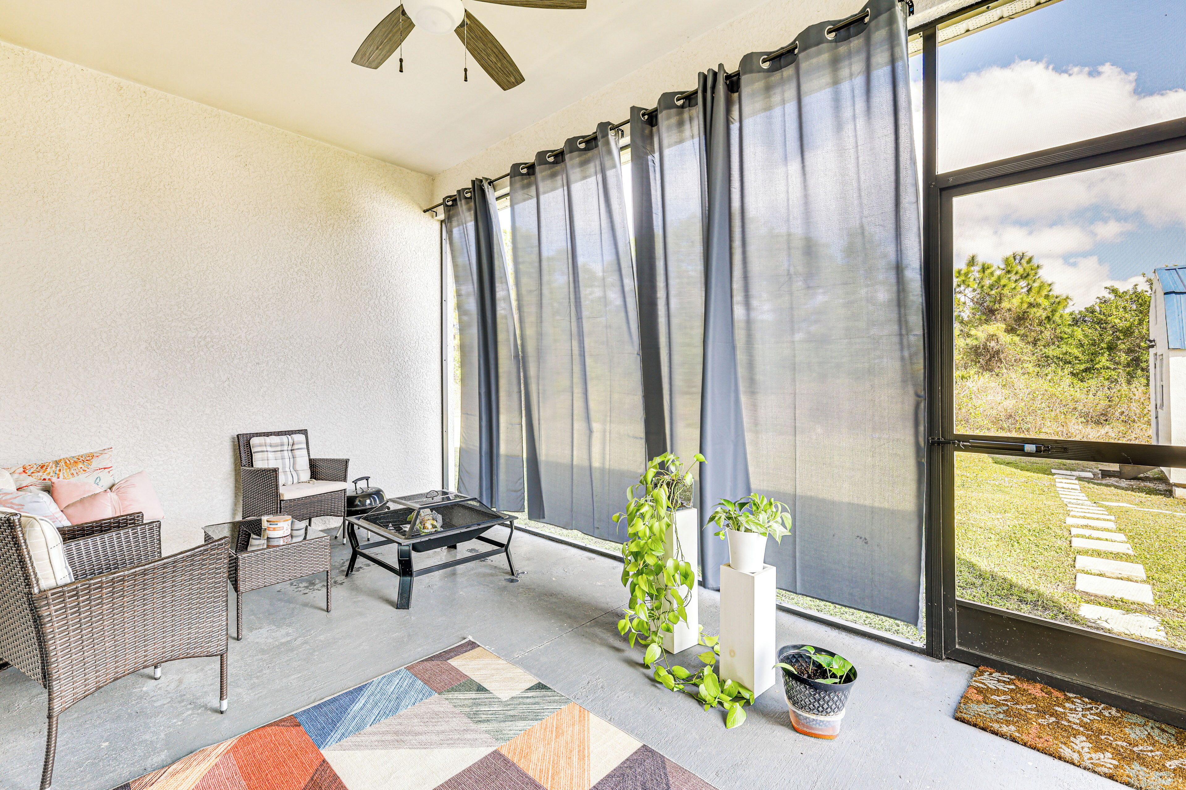 A modern living room with wicker furniture, a coffee table, and potted plants.