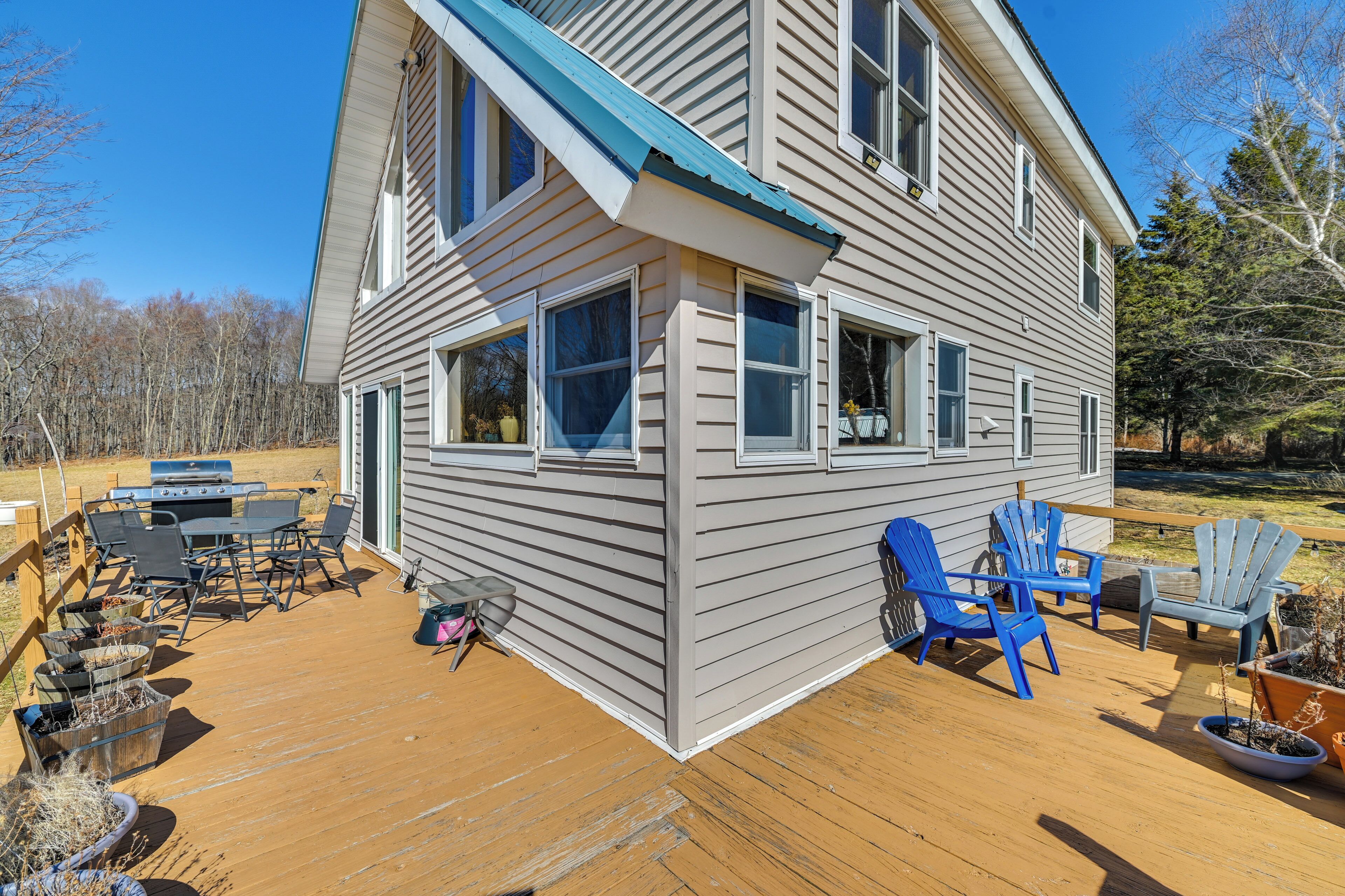 A two-story house with a deck, outdoor furniture, and a grill.