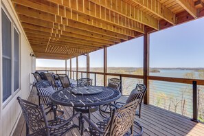 A covered outdoor deck with a round table and chairs, overlooking a body of water. - The Best Views on Beaver Lake! Home w/ Deck & BBQ (Rogers)
