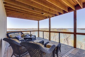 A covered outdoor seating area with wicker furniture and a view of a lake. - The Best Views on Beaver Lake! Home w/ Deck & BBQ (Rogers)