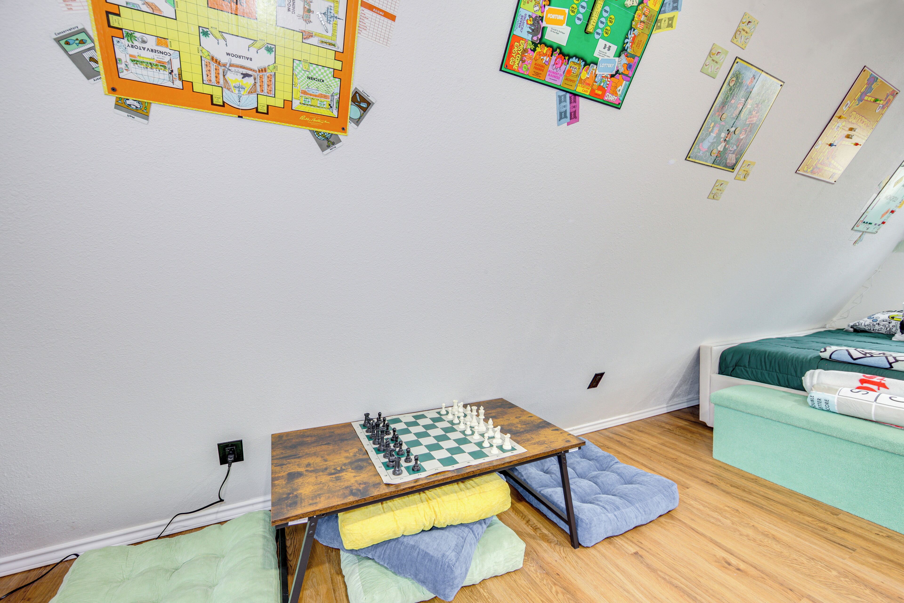 A bedroom with a wooden table, a bed with green bedding, and a small couch.