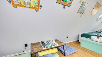 A bedroom with a wooden table, a bed with green bedding, and a small couch.