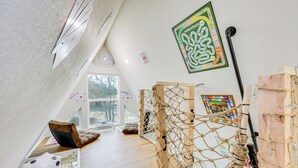 A room with a sloped ceiling, a large window, a wooden play structure, and a board game on the wall. - 7 Mi to Tyler State Park: 'a-game' Cabin (Tyler)