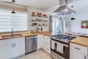 A modern kitchen with white cabinets, stainless steel appliances, wooden countertops, and a large window with blinds. - 3 Mi to Lake Wilderness: Charming Family Home! (Maple Valley)