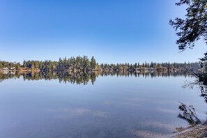 A calm lake with a forested shoreline and buildings in the background. - 3 Mi to Lake Wilderness: Charming Family Home! (Maple Valley)
