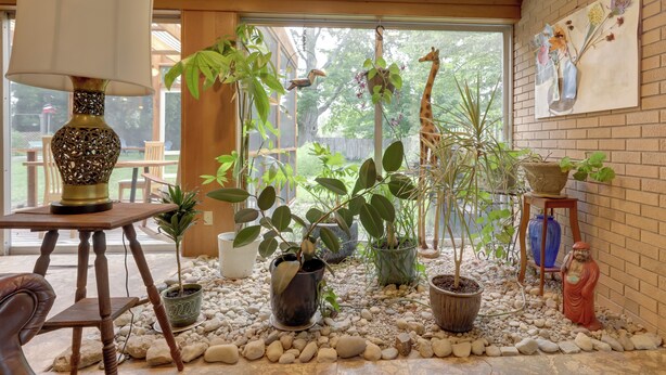 A room with a wooden table, a lamp, potted plants, a giraffe sculpture, and a painting on the wall. - Spacious & Updated Farmhouse in Yellow Springs (Yellow Springs)