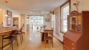 A spacious kitchen with wooden flooring, a dining area with a table and chairs, and a bar area with stools. - Spacious & Updated Farmhouse in Yellow Springs (Yellow Springs)