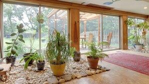 A spacious indoor area with large windows, potted plants, and a wooden floor. - Spacious & Updated Farmhouse in Yellow Springs (Yellow Springs)
