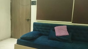 Une pièce avec un canapé bleu, un coussin rose et une porte en bois.