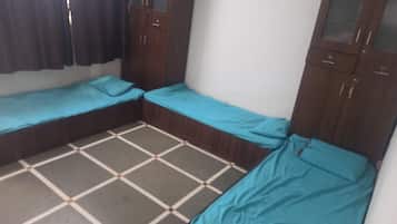 A small room with two single beds, a wardrobe, and a tiled floor.