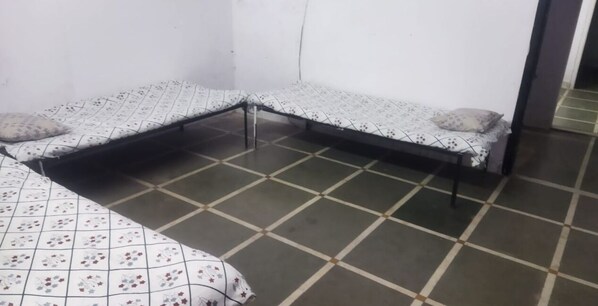 Una stanza con due letti, ognuno con una coperta e dei cuscini a fantasia, e un pavimento piastrellato.