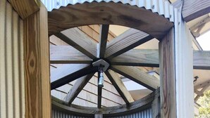 A wooden structure with a corrugated metal door and a ceiling with a scalloped edge.