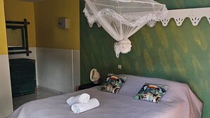 A neatly made bed with a white bedspread, a decorative pillow, and a rolled towel. - L'ECRIN BLEU SEA VIEW DIAMOND ROCK (LE DIAMANT)