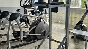 A gym with various exercise equipment, including a squat rack and cardio machines. - L'ECRIN BLEU SEA VIEW DIAMOND ROCK (LE DIAMANT)