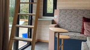 A wooden interior with a loft bed, a ladder, a sofa, and a small table. - Comfortable Tiny House in Saulges in the heart of nature. (Saulges)