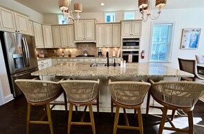 A kitchen with a granite island, stainless steel appliances, wicker bar stools, and pendant lighting. - New Listing * Stunning Bayside Resort 5BR Beach House w 4 Full B (Selbyville)