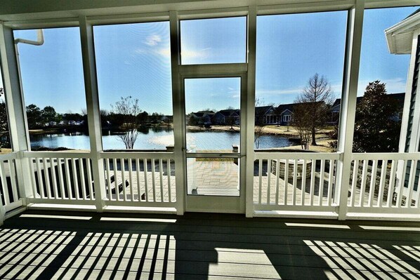 A covered outdoor area with a view of a lake and houses.