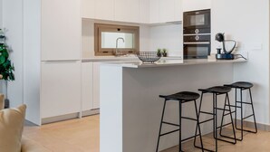 Une cuisine moderne dotée d’un îlot central, de tabourets de bar et d’appareils électroménagers intégrés.