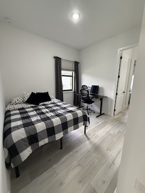 A bedroom with a bed, a desk, and a chair.