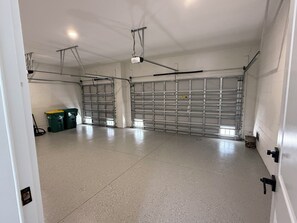 A spacious garage with a concrete floor, metal garage doors, and overhead lighting. - Modern oasis in the heart of southwest Florida - In-ground heated pool (Rotonda West)