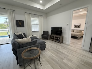 Una sala de estar moderna con un sofá modular, un televisor de pantalla plana y un comedor con mesa y sillas.