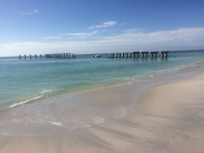 Una playa con un muelle que se adentra en el agua.