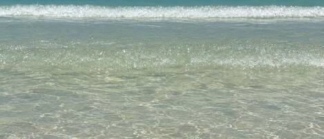 A beach with clear shallow water and gentle waves.