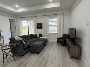 A modern living room with a sectional sofa, a television, and a small table.