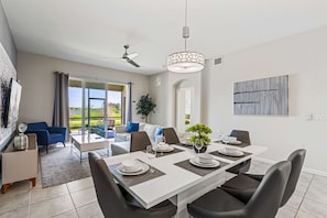 A modern dining area with a white table set for six, black chairs, and a ceiling fan. - Kissimmee Retreat: Cozy 2BR Condo near Theme Parks (Kissimmee)