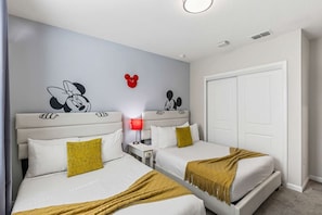 A hotel room with two beds, a wardrobe, a Mickey Mouse wall decal, and a red lamp. - Kissimmee Retreat: Cozy 2BR Condo near Theme Parks (Kissimmee)