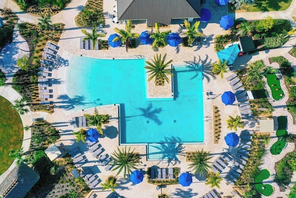 An aerial view of a resort with a central swimming pool, sun loungers, and palm trees. - Kissimmee Retreat: Cozy 2BR Condo near Theme Parks (Kissimmee)