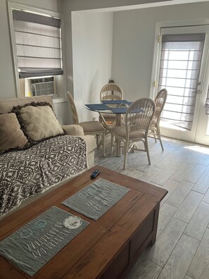 Una sala de estar amoblada con sofá, mesa de centro y mesa de comedor con sillas.